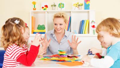 Vroegbehandeling in Helmond voor kind met TOS Vier kinderen en een behandelaar praten met elkaar
